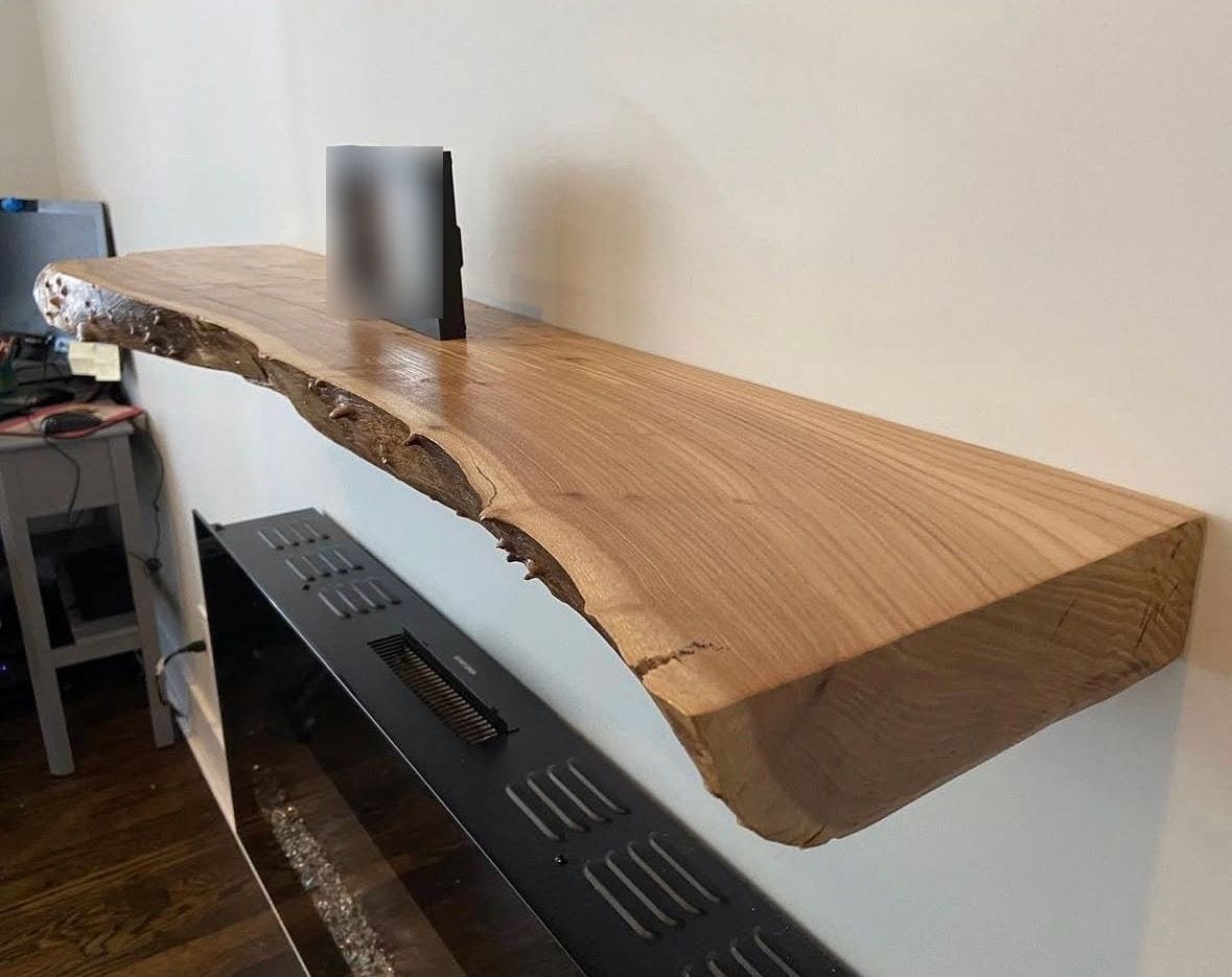 Thick live-edge floating shelf above a wall-mounted electric fireplace